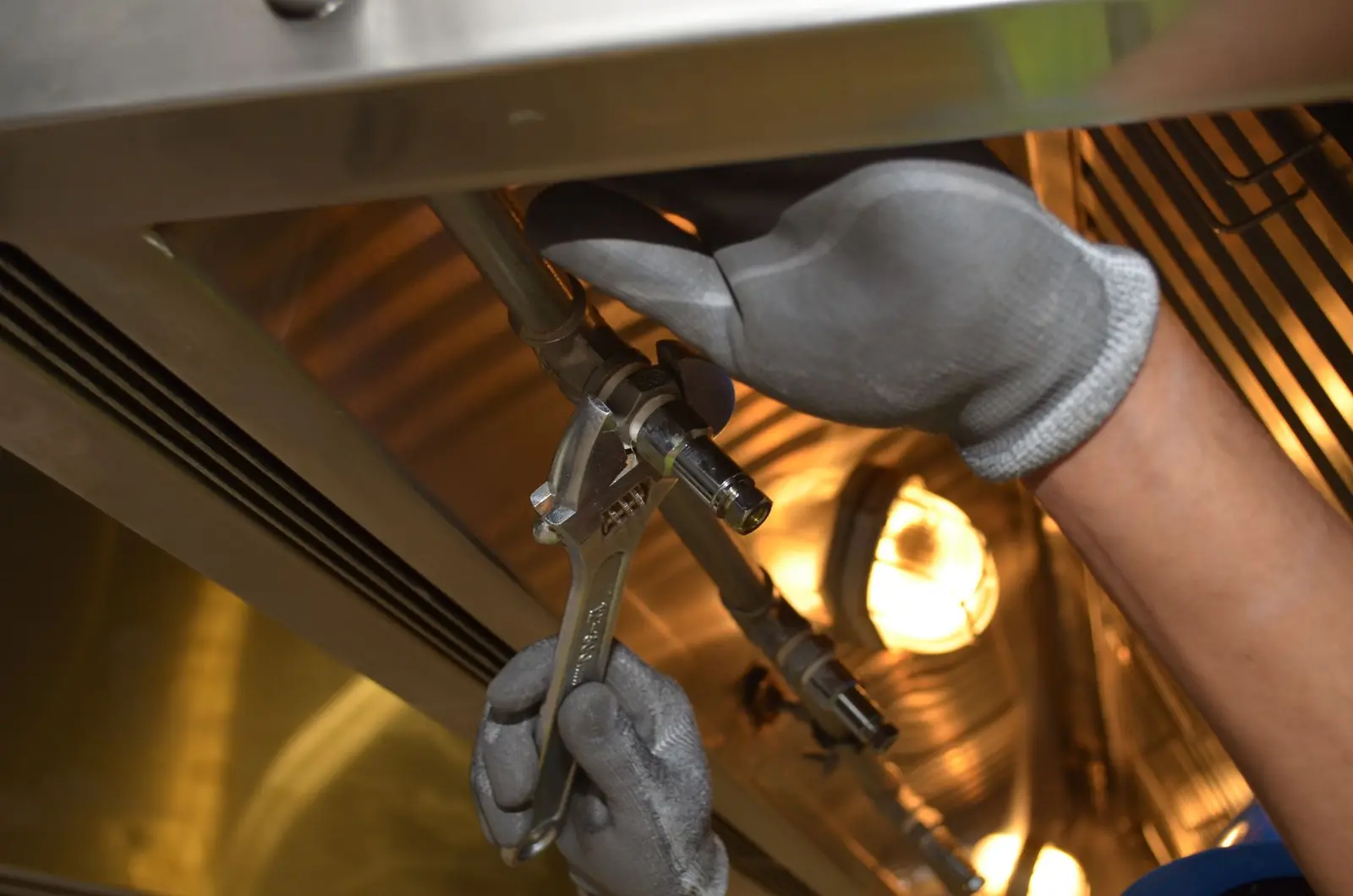 Plumbing technician tightening a water supply connection with two wrenches